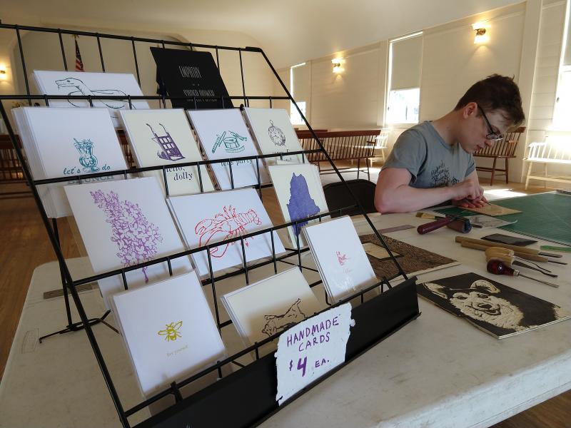 Jaime Wing, hard at work carving a new block, displays his greeting cards at Boothbay Railway Village Rori Smith photo.