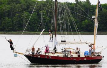 Pirate Vessel Must Roos: The pirate vessel Must Roos leads the attack on the Twin Villages during a past Pirate Rendezvous. “Must Roos” is Estonian for “Dark Rose,” the symbol of the Dark Rose Pirates. Courtesy of easternmaineimages.com