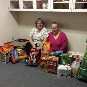 Donna Gregory, left, and Amylynn Balsdon, right, surrounded by the pile of donations made to the Lincoln County Animal Shelter as part of their event. KATRINA CLARK/Boothbay Register