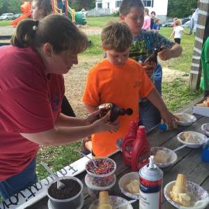 Kristy Lincoln, left, helps son Chris Lincoln make an ice cream treat at Partners in Education’s ice cream social at the Wiscasset community playground June 10. SUSAN JOHNS/Wiscasset Newspaper